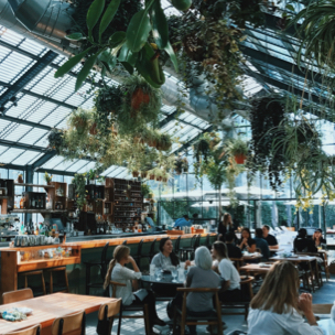 restaurant in a greenhouse with lots of plants hanging around